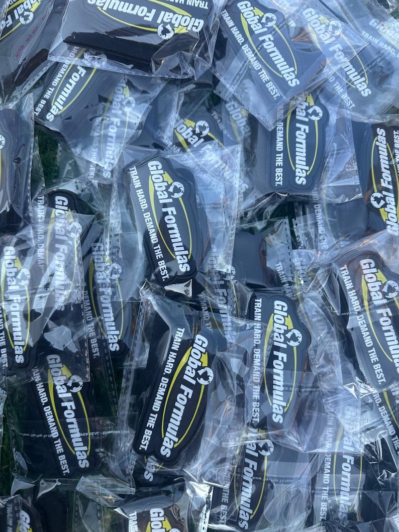 May include: A collection of black and yellow Global Formulas keychains in clear plastic packaging. Each keychain has the text "Global Formulas" and "Train Hard. Demand the Best."