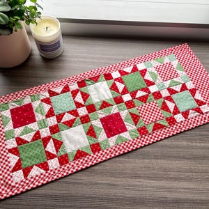 Peut inclure: Un chemin de table en patchwork rouge et vert avec une bordure à carreaux. Le chemin de table est composé de carrés de tissu de différents motifs et couleurs.