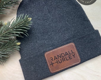 May include: Black beanie with a brown leather patch that says "RANDALL + HURLEY" in white lettering.