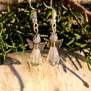 May include: Silver angel dangle earrings with clear crystal teardrop charms. The angels have rhinestone accents.