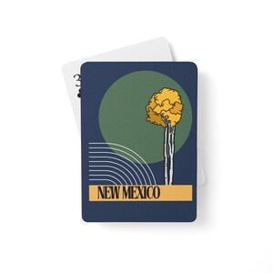 May include: A playing card featuring a stylized illustration of a tree with yellow foliage against a green circle and a navy blue background. The card also has the text "NEW MEXICO" in a gold rectangle.