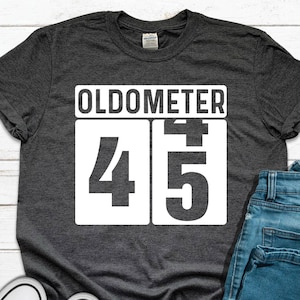 May include: A dark gray t-shirt with a white graphic that says "Oldometer 45".