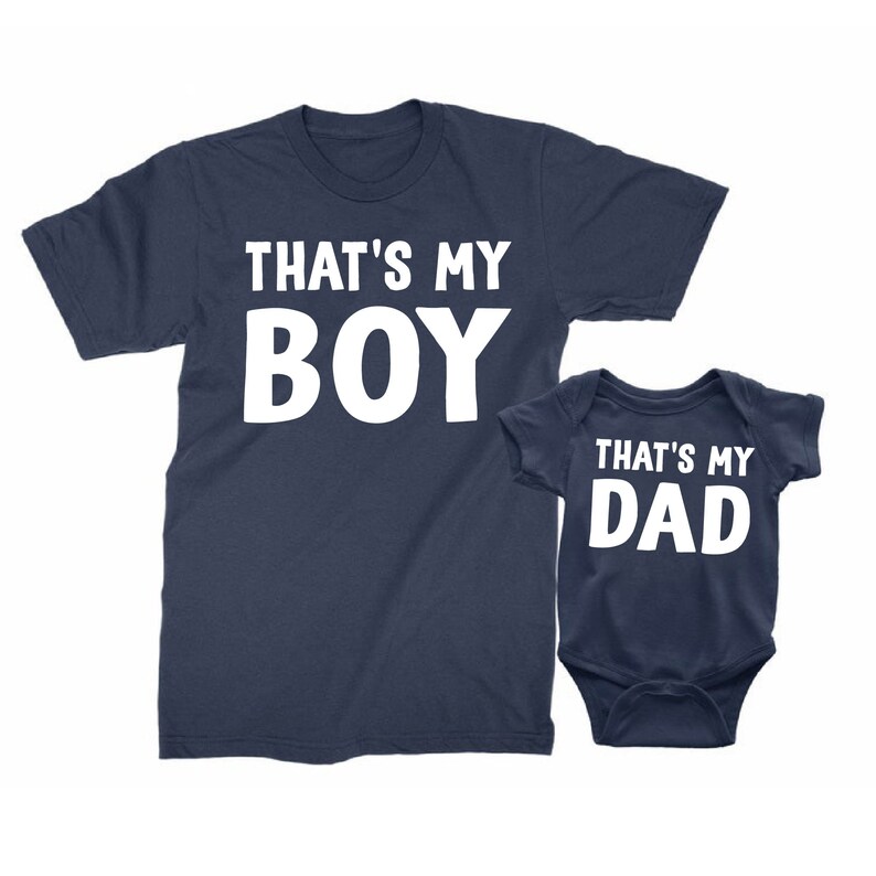 May include: A navy blue t-shirt with the text "That's My Boy" in white, and a navy blue baby bodysuit with the text "That's My Dad" in white.