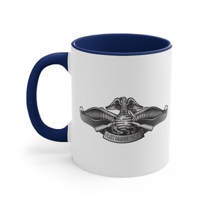 Op de afbeelding: Witte keramische koffiemok met een donkerblauwe rand en handvat. De mok heeft een zilveren afbeelding van het Fleet Marine Force-embleem met de woorden "Fleet Marine Force" eronder gedrukt.