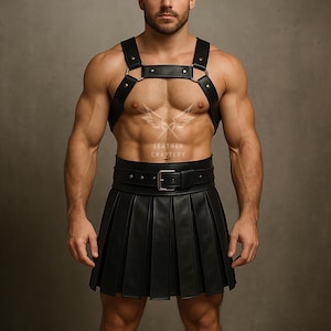 Pode incluir: Arn&ecirc;s e kilt plissado em couro preto. O arn&ecirc;s apresenta uma tira no peito e al&ccedil;as conectadas por an&eacute;is de metal. O kilt tem um cinto com fivela prateada. O texto "LEATHER CRAFTERY" &eacute; vis&iacute;vel.