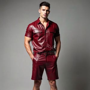 May include: A burgundy leather shirt and shorts set. The short-sleeved shirt has two chest pockets and a button-down front. The shorts have a matching belt. The set is worn by a person.