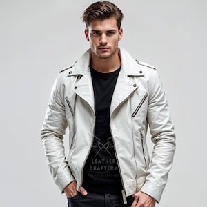Puede incluir: Chaqueta de cuero blanca de estilo motero clásico, con cuello con solapas, cremallera asimétrica y múltiples bolsillos con cremallera. Se lleva sobre una camiseta negra. La imagen incluye el texto "LEATHER CRAFTERY".