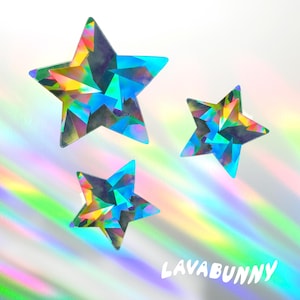 May include: Three iridescent star-shaped stickers with a geometric design. The stickers have a rainbow color scheme with shades of blue, yellow, green, and purple. The word "LAVABUNNY" is written in white script at the bottom right.