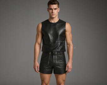 Könnte beinhalten: Ein schwarzes ärmelloses Oberteil aus Leder und passende Shorts mit Reißverschlussdetails. Das Outfit besteht aus glänzendem, glattem Material. Das Model steht vor einem grauen Hintergrund.