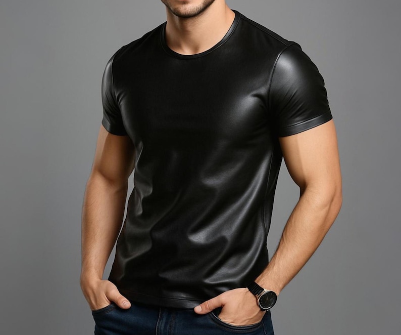 Puede incluir: Una camiseta negra de cuero de manga corta y cuello redondo. La camiseta tiene una textura lisa y brillante. El modelo lleva un reloj negro y vaqueros azules.