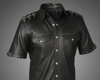 May include: Black leather short-sleeve shirt with silver button closures and two chest pockets. The shirt features decorative silver buckles on the shoulders and sleeves, and a classic collar. A stylish garment for a bold look.