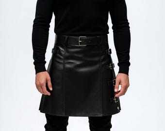 Könnte beinhalten: Schwarzer Lederkilt mit Gürtel und Schnallenverschluss. Der Kilt hat drei dekorative Schnallen an der Seite und besteht aus einem glatten, einfarbigen Material. Der Kilt wird mit einem schwarzen Langarmshirt und einer schwarzen Hose getragen.