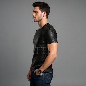 Puede incluir: Camiseta negra efecto cuero con mangas cortas y cuello redondo. La camiseta tiene un corte entallado. El modelo lleva vaqueros azules y un reloj negro. El logo TTI es visible en la camiseta.