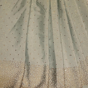 May include: A light blue fabric with a subtle shimmer and a border of small, gold-toned rhinestones.