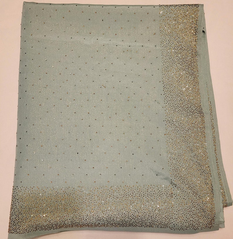 May include: A light blue scarf with a border of silver sequins. The scarf is made of a soft, silky material.