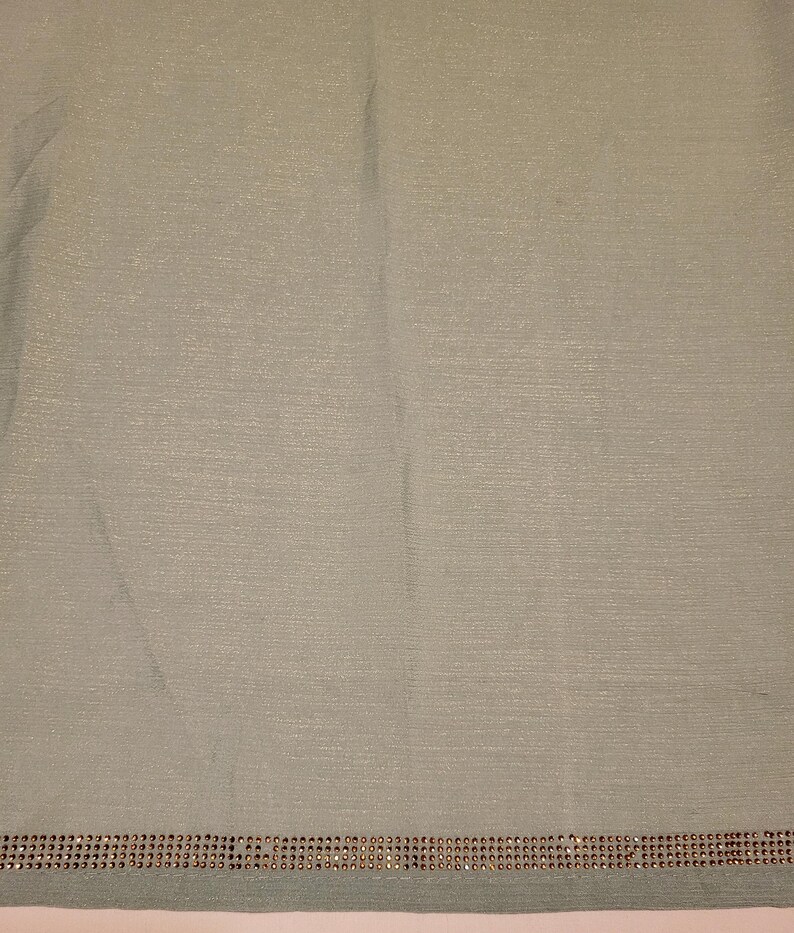 May include: A light green fabric with a silver shimmer and a row of rhinestones along the bottom edge.