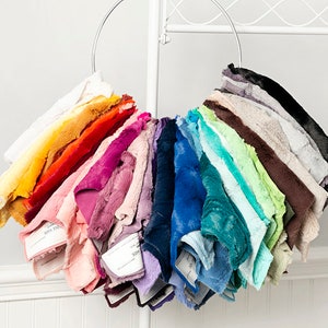 May include: A variety of faux fur fabric swatches in different colors are displayed on a metal ring. The swatches are arranged in a rainbow pattern, with white at the top and black at the bottom.