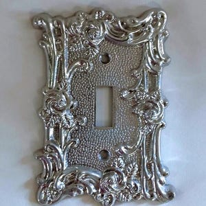 1967 American Tack & Hardware Co. Silver Alloy Single Light Switchplate Cover Framed With Raised And Textured Roses And Scroll Designs