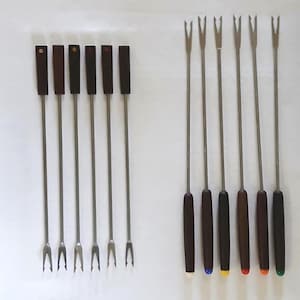 May include: A set of fondue forks with stainless steel tines and long, slender stems. The handles are made of dark wood. One set has rectangular handles, and the other has rounded handles with colored tips.
