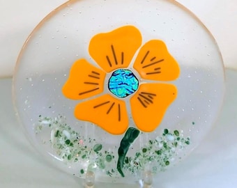 Fused Glass Art 8 3/4" Plate With A Yellowish Orange Flower With Metallic Blue And Gold Center. The Green Stem And Ground Of Frit Glass
