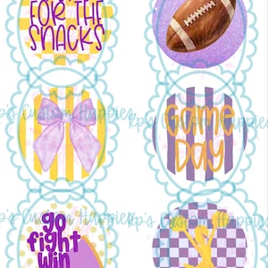 Puede incluir: Una hoja de seis pegatinas circulares festoneadas con diseños deportivos. Los gráficos incluyen un balón de fútbol americano, un lazo morado, una animadora y el texto Here For The Snacks, Game Day y Go Fight Win en amarillo y morado.