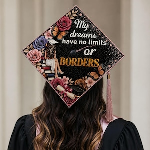 May include: A decorated graduation cap with the words "My dreams have no limits or borders." The cap is black with floral and butterfly accents, a tassel, and a seated figure. The design includes roses, butterflies, and a graduation scroll.
