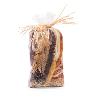 May include: A clear plastic bag filled with dried autumn harvest items, including yellow and blue speckled corn cobs, golden wheat stalks, dark brown millet, and dried husks. The top of the bag is gathered and tied with a natural tan raffia ribbon.