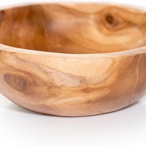 May include: A large, natural wood bowl with a rounded shape and a smooth, light brown finish. The bowl has a natural wood grain pattern.