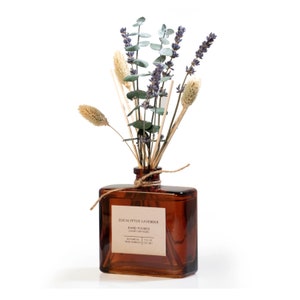 May include: A brown glass bottle diffuser with a label that reads "Eucalyptus Lavender Hand Poured Luxury Diffuser Botanical 7 FL OZ Reed Diffuser 200 ML". The bottle is filled with a clear liquid and has a bouquet of dried lavender, eucalyptus, and dried grasses.
