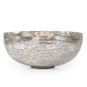 May include: A silver-colored decorative bowl with a textured surface. The bowl has a wide, shallow shape and sits on a small, round base. The bowl's exterior has a mottled appearance.