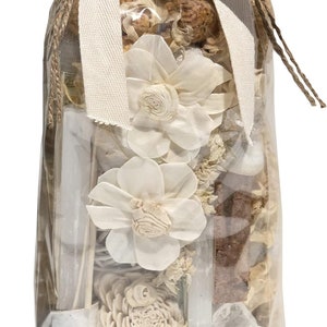 May include: A clear plastic bag filled with a variety of dried flowers, wood pieces, and crystals. The bag is tied with a white ribbon and a tag that reads "ANDALUCICA."