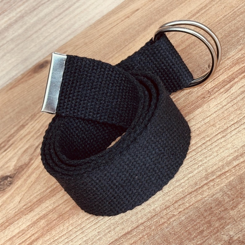 May include: A black canvas belt with a silver double ring buckle.