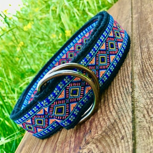 May include: A black dog collar with a colorful geometric pattern in shades of blue, pink, orange, and yellow. The collar has a silver D-ring.