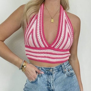 Puede incluir: Un top de crochet halter a rayas rosa y blanco con un escote en V profundo. El top es corto y tiene un ajuste holgado.