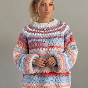 May include: A long-sleeve crochet sweater featuring a horizontal striped pattern in shades of light blue, soft pink, white, and muted purple. The garment has a thick ribbed white crew neckline and matching ribbed cuffs, with a chunky textured knit.