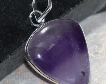 May include: A triangular amethyst pendant with a silver-colored metal frame and bail. The polished purple gemstone has a smooth surface and a small dark inclusion. The pendant is designed for wear as a necklace.