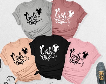 May include: Four t-shirts with the text "Girls Trip" and a Mickey Mouse head balloon graphic. The shirts are in different colors: gray, pink, black, and peach.