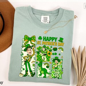 A light green t-shirt with a cartoon character design and text related to St. Patrick's Day, along with a brown hat and a fan.