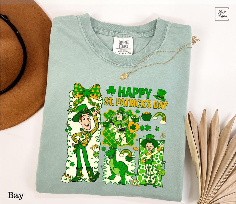 A light green t-shirt with a cartoon character design and text related to St. Patrick's Day, along with a brown hat and a fan.