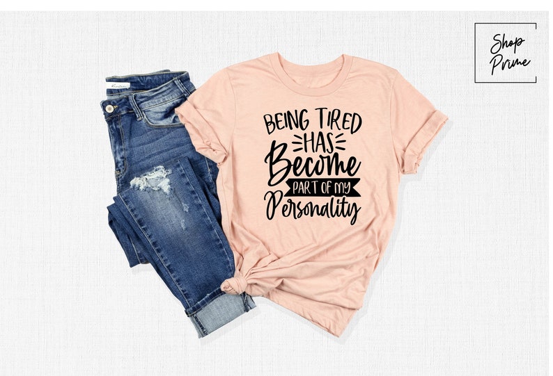 Może przedstawiać: R&oacute;żowy t-shirt z czarnym nadrukiem: "Bycie zmęczonym stało się częścią mojej osobowości".