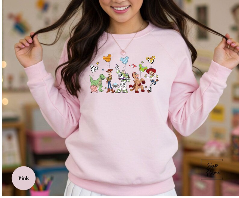 A woman wearing a pink sweatshirt with a cartoon character design on it.
