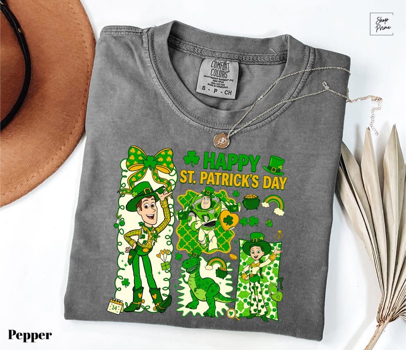 A gray t-shirt with a cartoon character design and text related to St. Patrick's Day, along with a necklace and a hat.