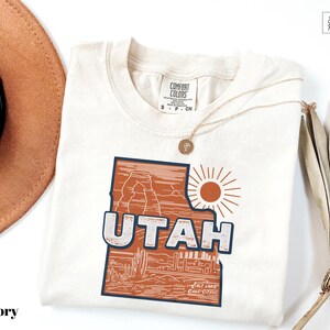 a hat, sunglasses, and t - shirt on a white surface