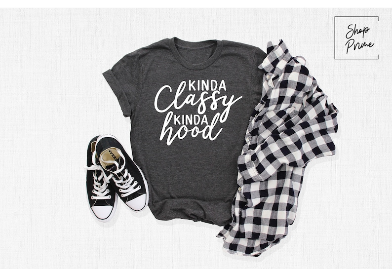 May include: A dark gray t-shirt with the text "Kinda Classy Kinda Hood" in white lettering.
