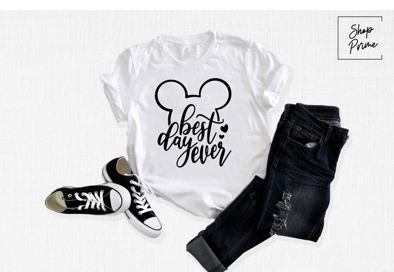 May include: White t-shirt with a black Mickey Mouse ears design and the text "best day ever" in black script.