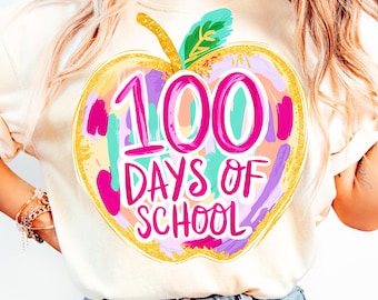 May include: A light beige t-shirt with a colorful graphic of an apple with the text "100 Days of School" on it.