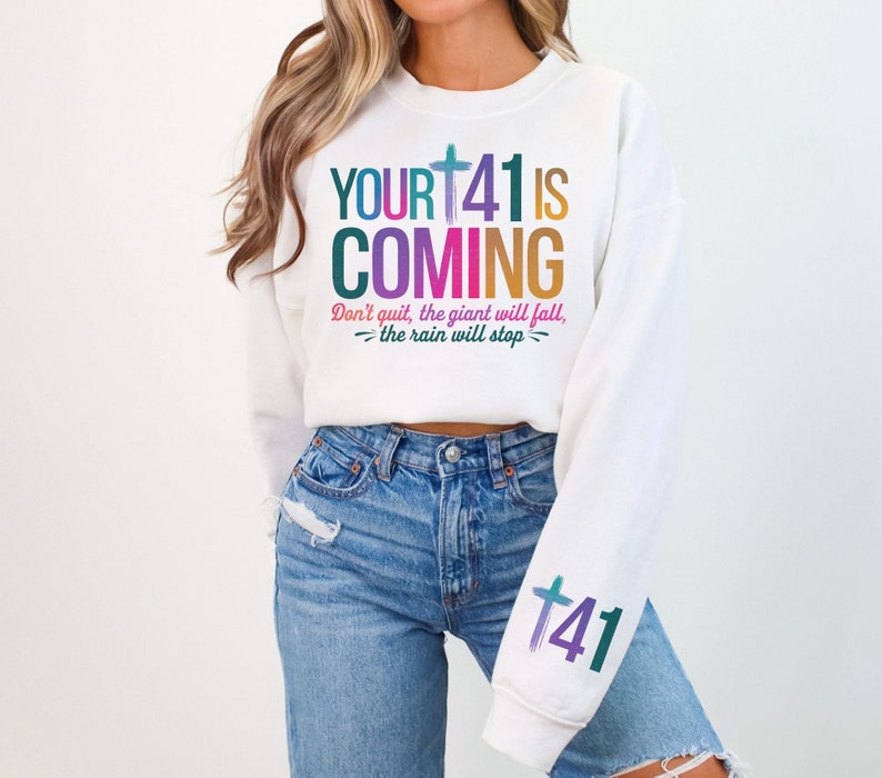 May include: White sweatshirt with a colorful graphic that says "YOURT41 IS COMING" and "Don't quit, the giant will fall, -the rain will stop-". The sweatshirt also has a colorful graphic of a cross and the number "41" on the sleeve.