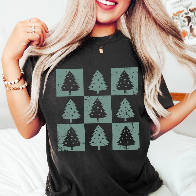 Puede incluir: Una camiseta negra con un dise&ntilde;o desgastado de nueve &aacute;rboles de Navidad verdes con adornos blancos.