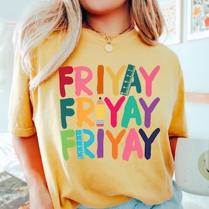 May include: A yellow t-shirt with the word "FRIYAY" written in colorful letters, with a pencil and ruler graphic in between each word.