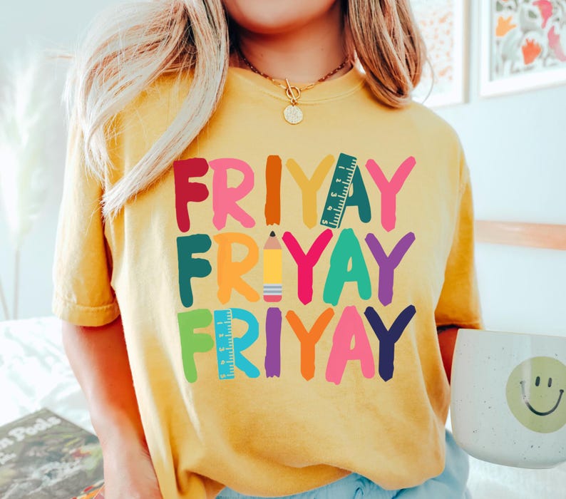 May include: A yellow t-shirt with the word "FRIYAY" written in colorful letters, with a pencil and ruler graphic in between each word.